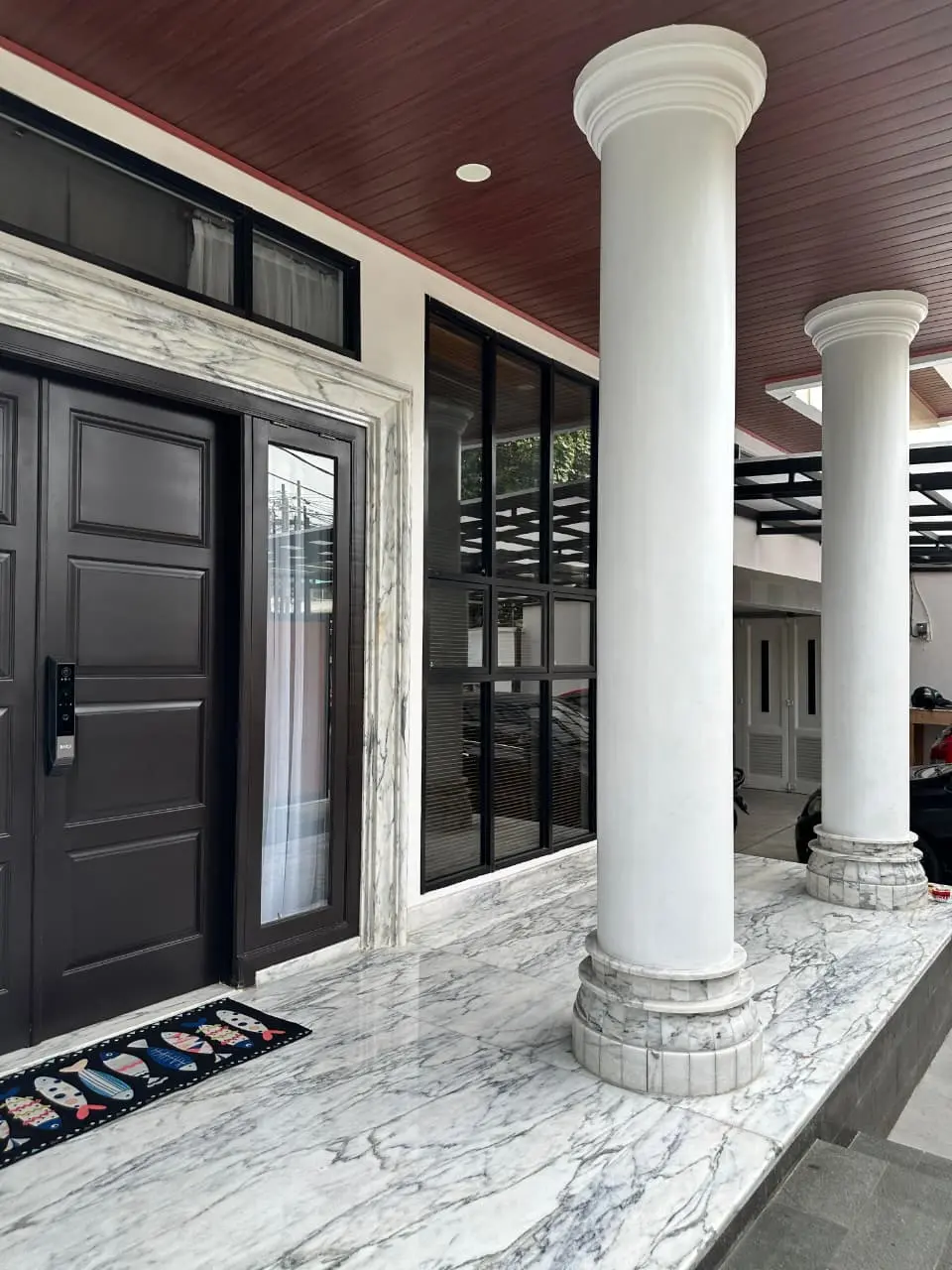 Teras depan rumah dengan kolom klasik dan lantai marmer